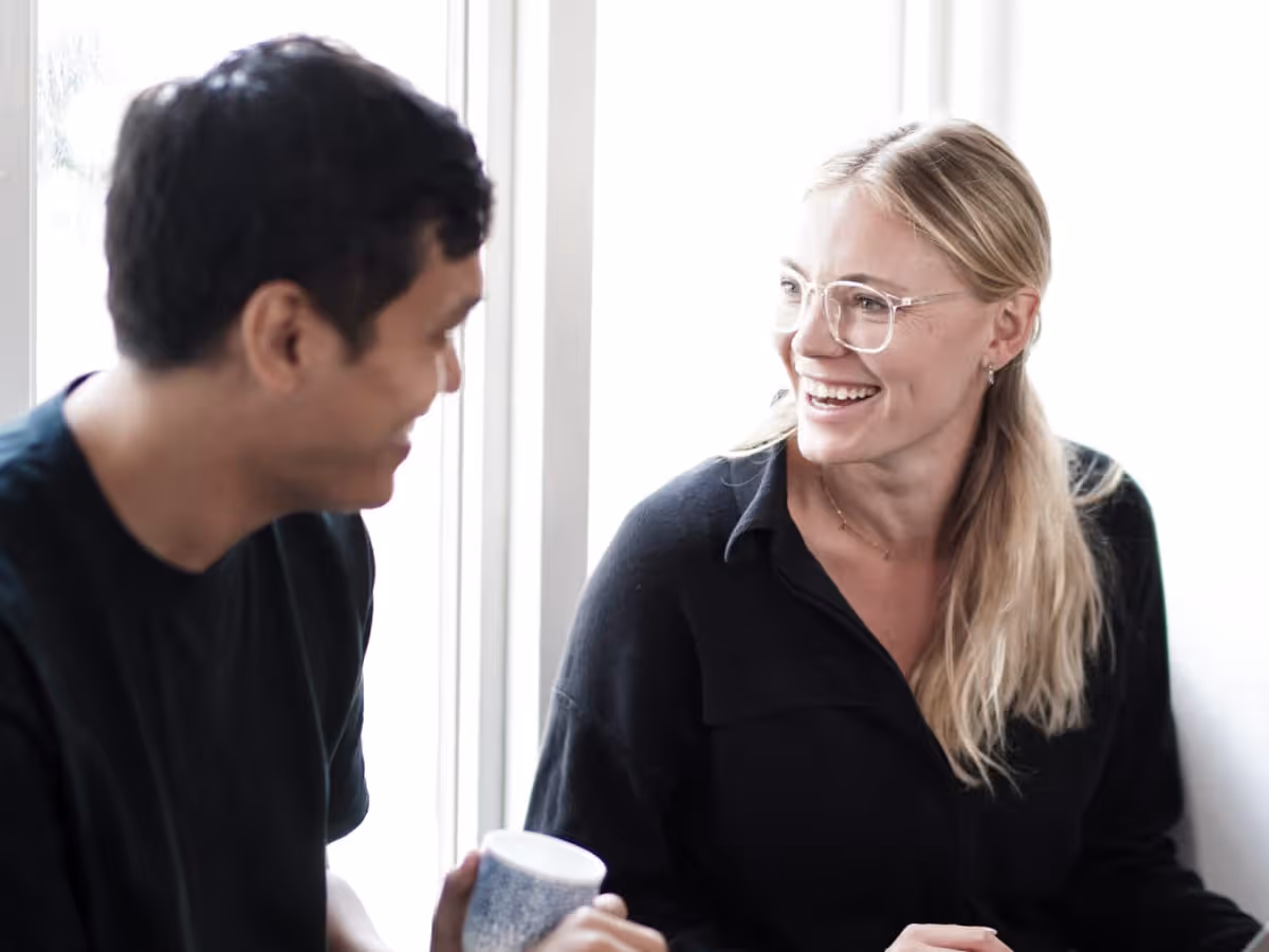 Jenny Holm and Noel Braganza, co-founders of One AI Advisory, talking beside a studio window
